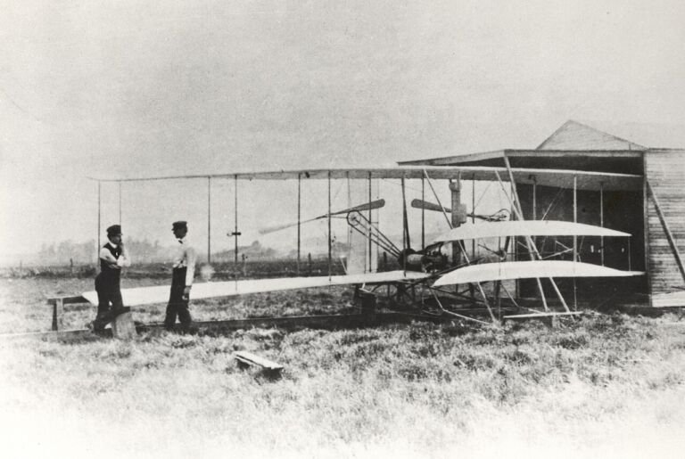 Wilbur y Orville Wright junto a su avión Flyer II en la pradera de Huffman