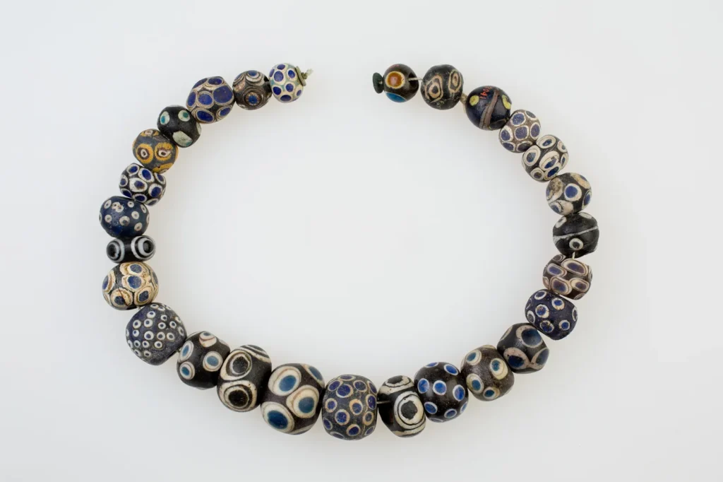 Collar abierto de cuentas redondas de vidrio oscuro decoradas con ojos azules y blancos