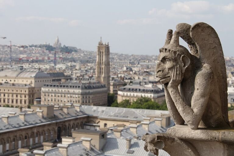 Quimera de piedra sin función de desagüe en lo alto de Notre-Dame de París, con la ciudad al fondo